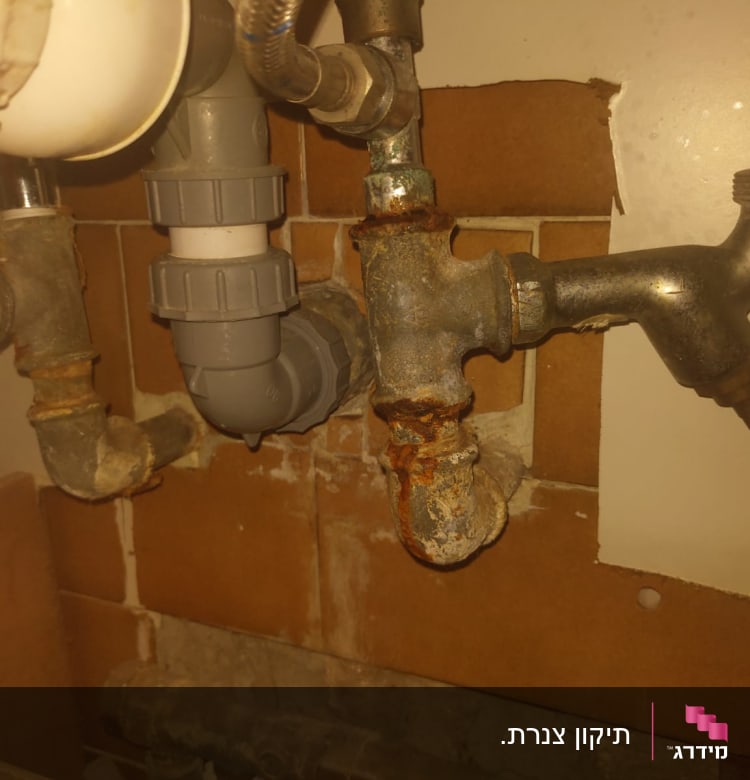 צינורות מתכת חלודים עם חיבורים מתחת לכיור